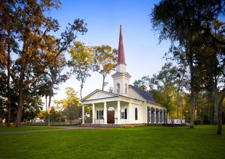 White chapel with red steeple surrounded by trees