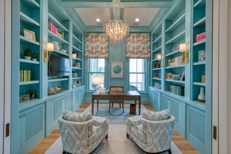 Elegant home office with blue built-in bookshelves and chandelier