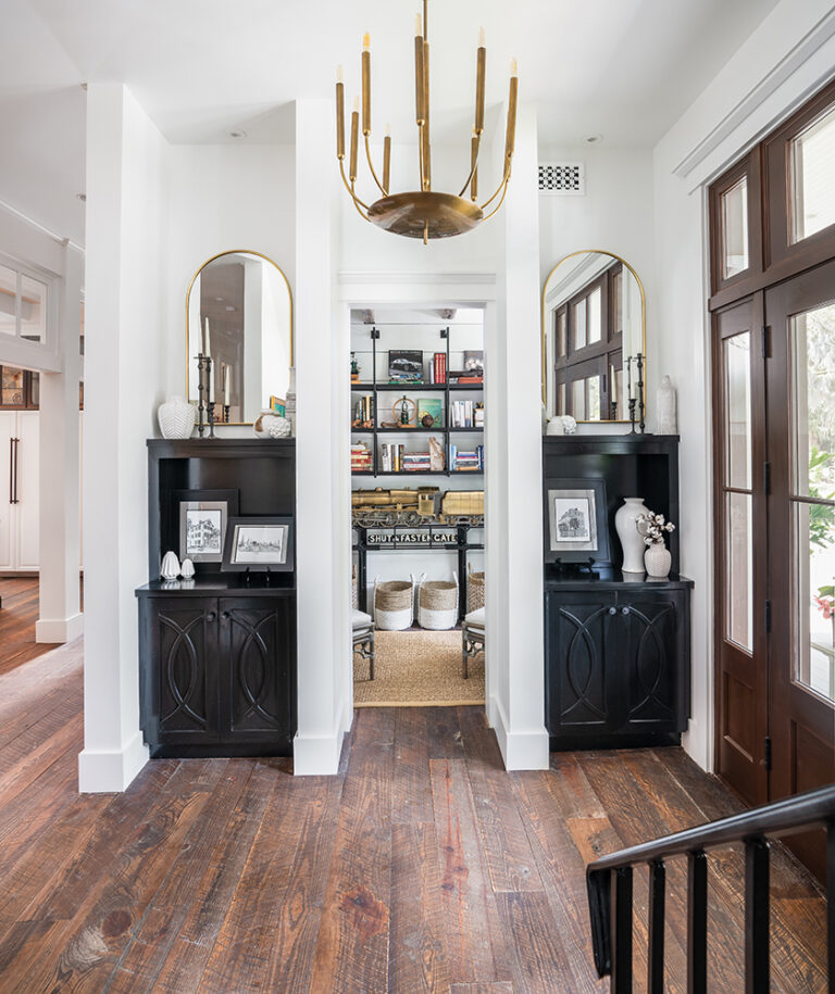 Entryway with built-in shelves, hardwood floors, and statement chandelier