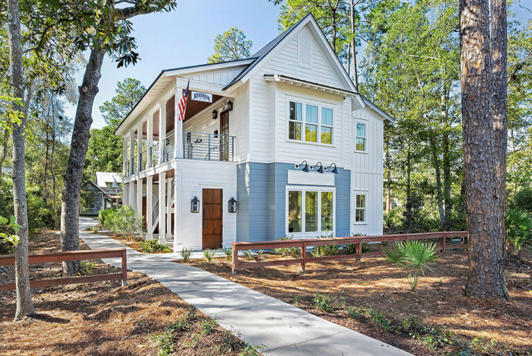 Modern white commercial building with gable roof and oversized windows.