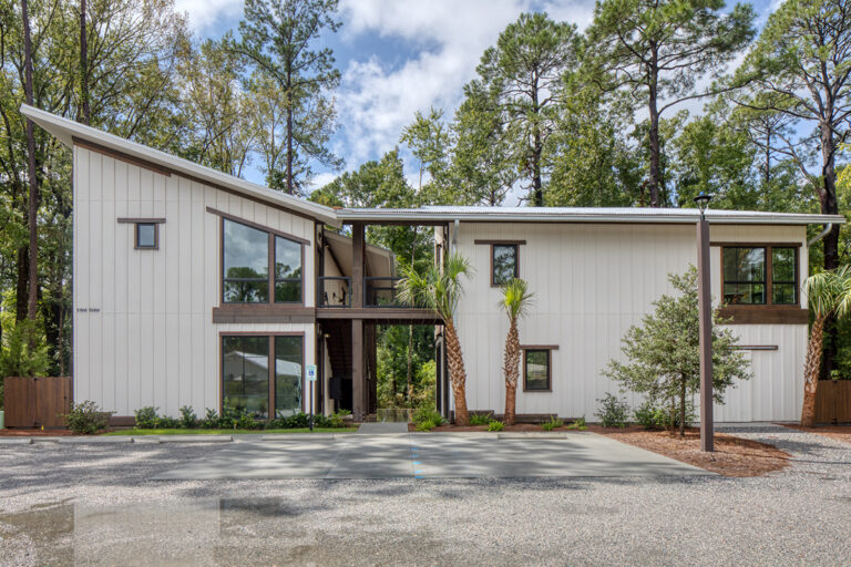 Rear view of a white commercial building with metal roof and gravel lot.