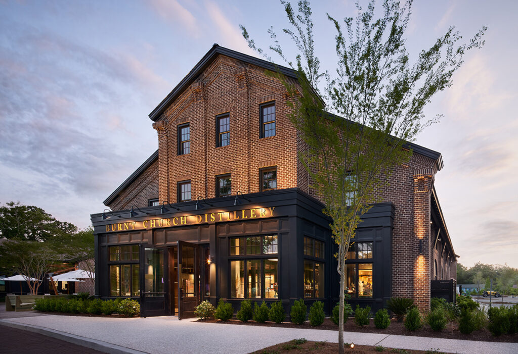 Burnt Church Distillery's brick building with black trim at twilight.
