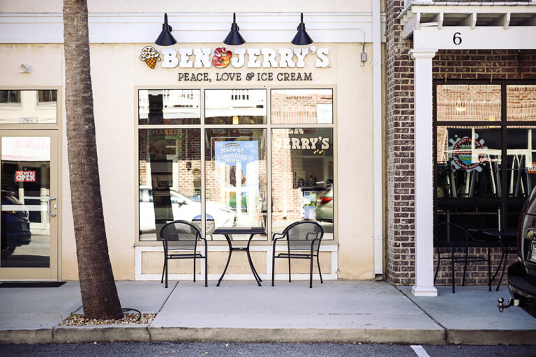 Exterior of Ben & Jerry’s shop with black and white signage and patio seating.