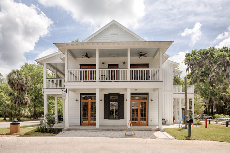 Mixed-use building with columns, upper-level balconies, and wood doors.