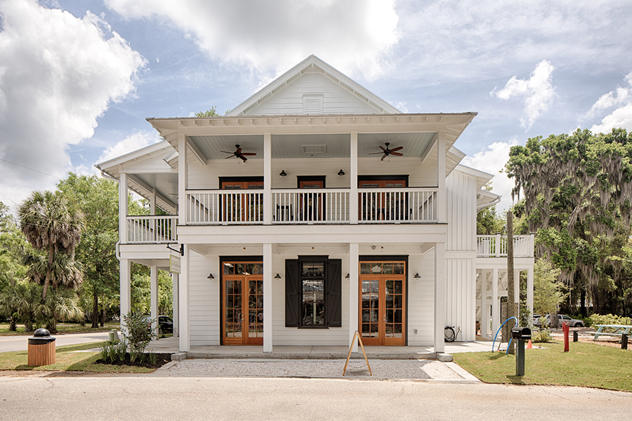 Mixed-use building with columns, upper-level balconies, and wood doors.