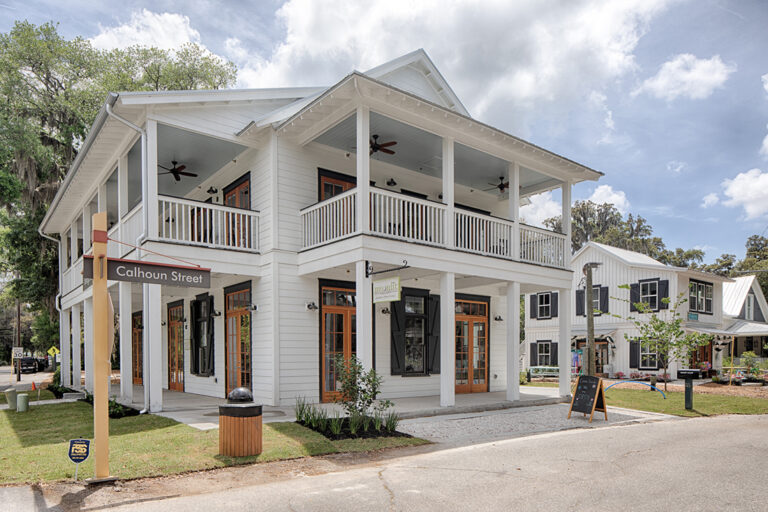 Corner view of mixed-use building with two-story porches and storefronts.