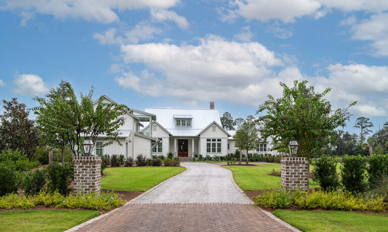 Exterior view of a white house with a paved driveway leading up to it.