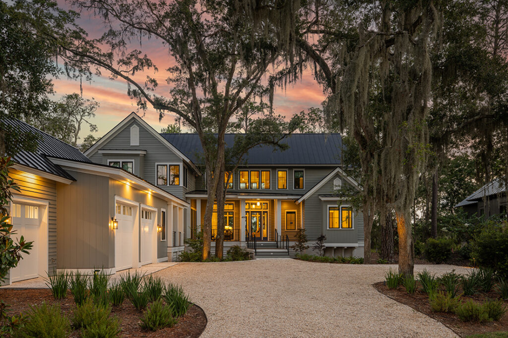 Warmly lit home exterior at dusk with gravel driveway.