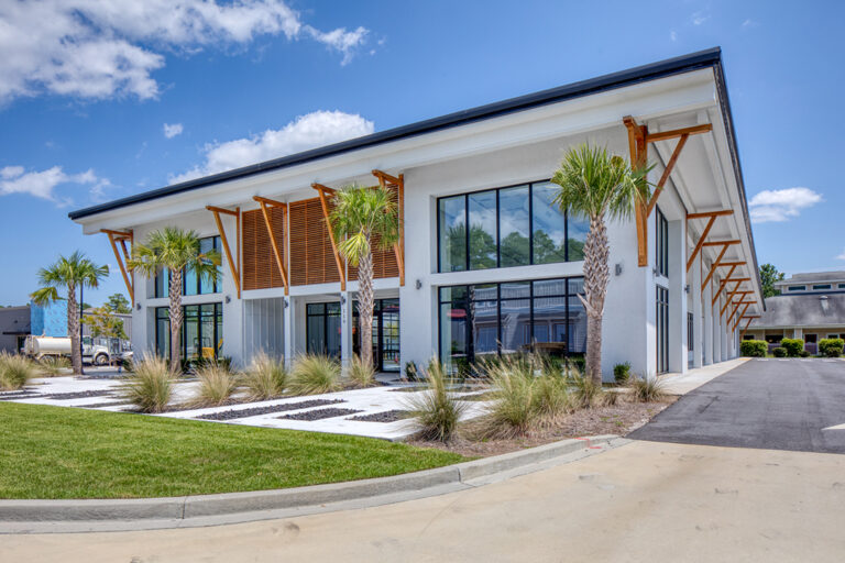 Contemporary office building with palm trees and clean landscaping.
