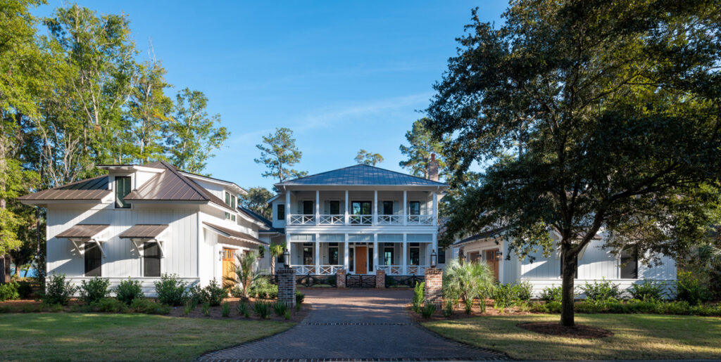 Exterior view of a large, traditional white house with columns and a wide front lawn, from a slightly different angle.