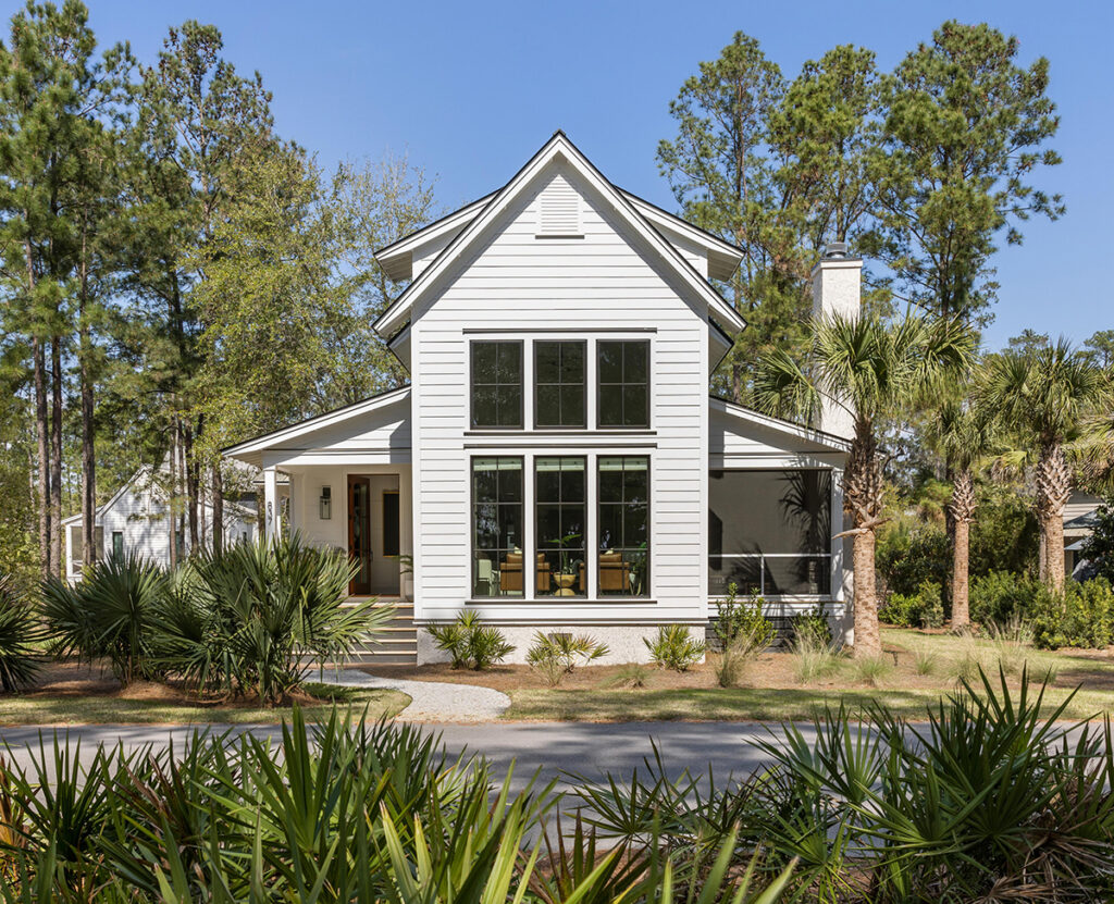 White modern farmhouse exterior with tall windows and metal roof.