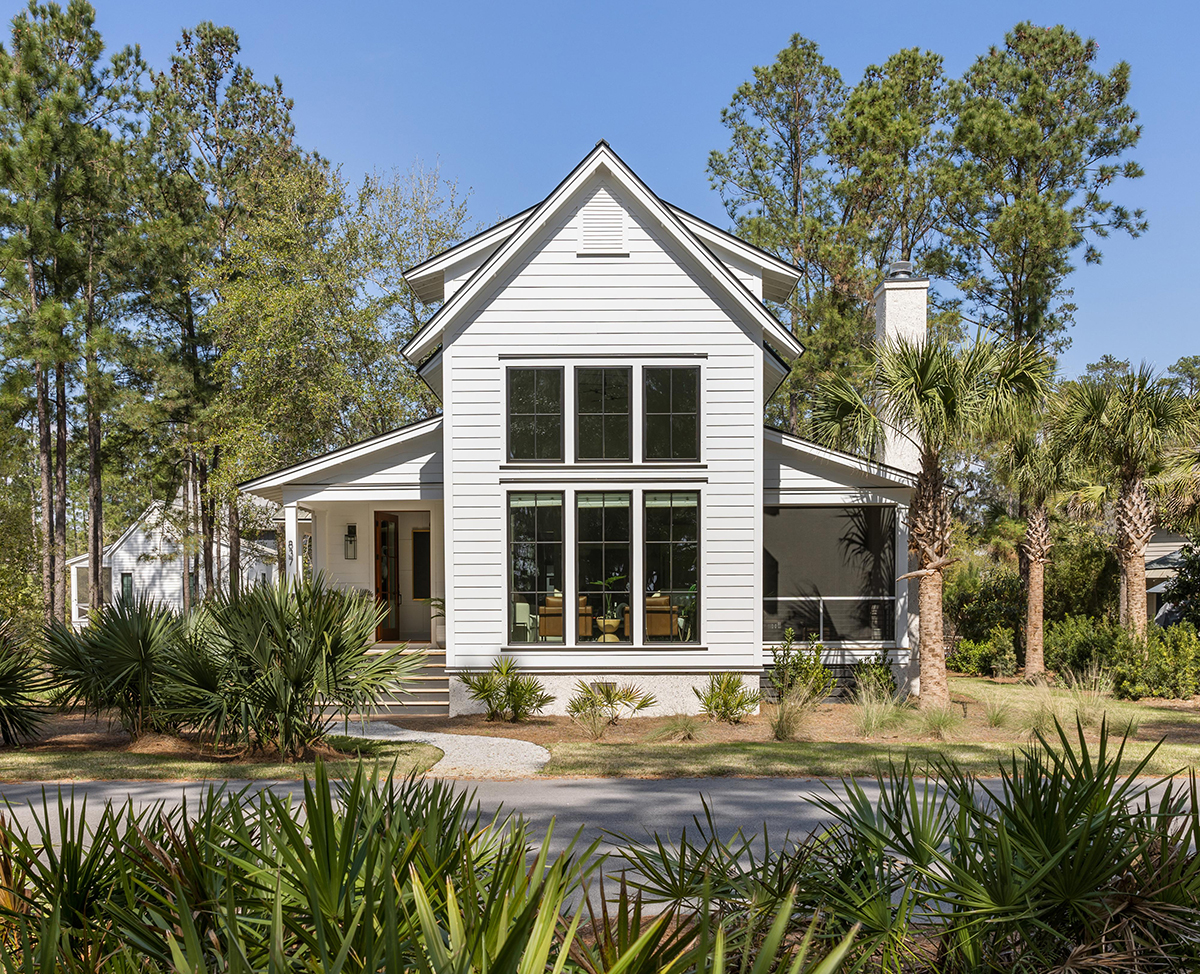 White modern farmhouse exterior with tall windows and metal roof.