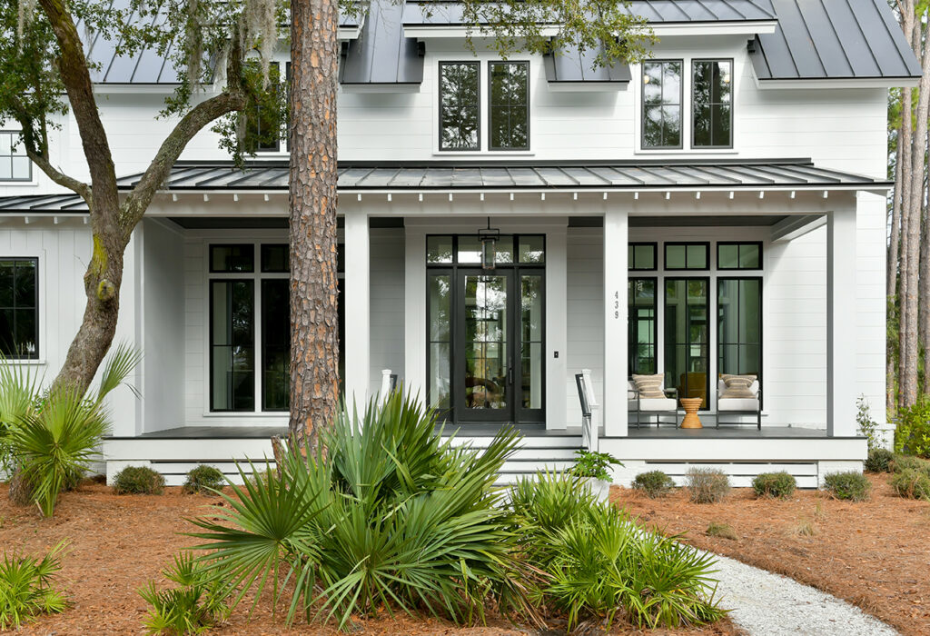 Another view of a Lowcountry-style home with front porch and lush landscaping.