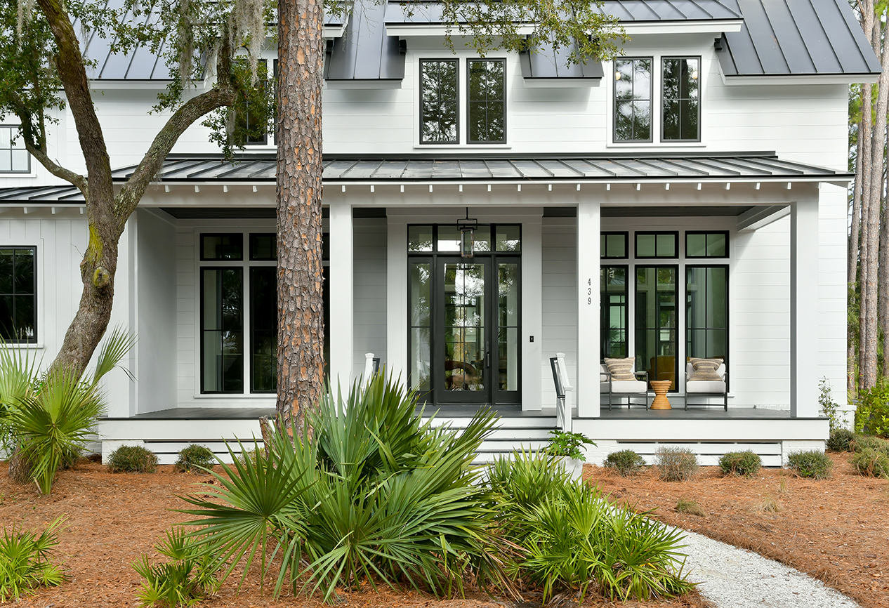 Another view of a Lowcountry-style home with front porch and lush landscaping.