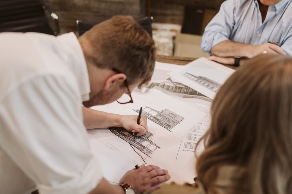 Close-up of hands drawing architectural elevations with pens.