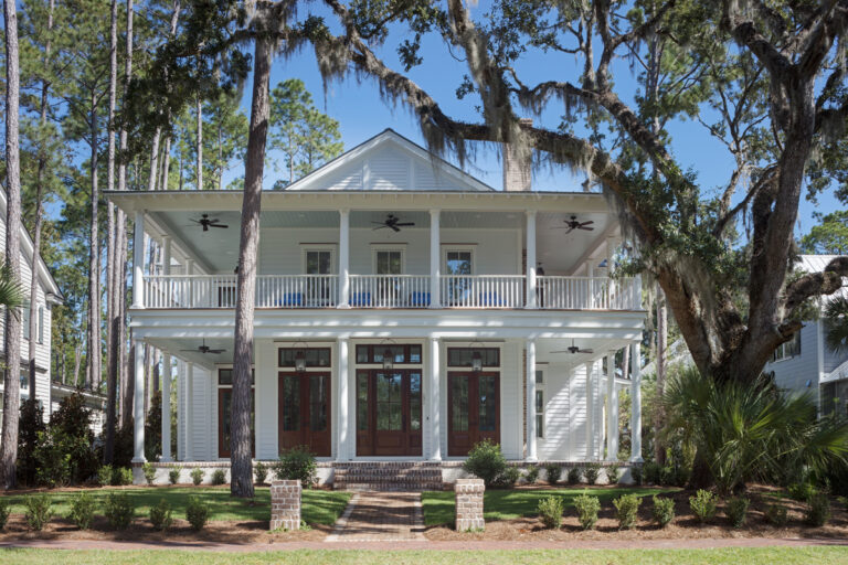 A traditional Southern home with antebellum style architecture that includes double porches with fans on the ceiling
