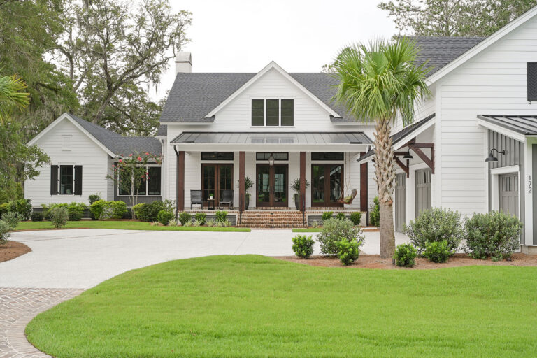Front exterior of a custom Lowcountry home with white siding, brick steps and covered porch
